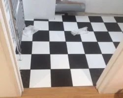An image of a bathroom which has been fitted with some new plumbing and a new tile patter vinyl floor